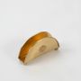 High angle view of the semi circular gold brass napkin holder with ball feet standing empty against a clean white background.