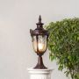 Brown pillar lamp glowing warmly on stone pillar for outdoor entrance lighting and stylish home garden pathway illumination.