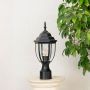 Stylish black pillar light with transparent glass shade placed on stone base ideal for villa entrance and terrace decor.