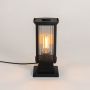 Black metal pillar light with ribbed clear glass glowing softly on white background for modern outdoor garden lighting decor.