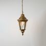 Elegant gold hanging lantern light glowing on white background showcasing textured glass and ornate detailing.