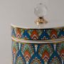 Closeup of multicolor ceramic jar showing intricate geometric pattern and shiny crystal knob lid with gold detail.