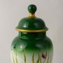 Closeup of ceramic jar showing detailed butterfly artwork and glossy green finish with golden accent rim.