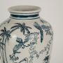 Blue and white ceramic jar featuring hand painted birds and palm motifs shown in close detail creating a refined decorative accent suited for elegant interior styling.