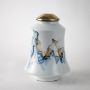 White ceramic jar with gold lid and blue mountain design shown on plain background for elegant artistic décor.