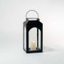 Black metal lantern with glass panels and lit candle displayed on white background for modern decor.