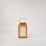 Wooden solar lantern with light on featuring frosted glass panels and a sleek black solar panel top against a white background.