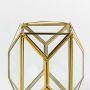 Closeup of gold geometric lantern highlighting refined metal edges and clear glass panels creating a premium modern decorative piece for interiors.