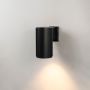 Black cylindrical wall light glowing on white background showcasing ribbed metal finish and modern minimalist form.
