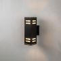 Black rectangular wall light glowing on white background highlighting geometric lines and soft frosted detailing.