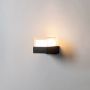 Sleek black and white square wall light illuminated on a white background showing its simple elegant and modern form.