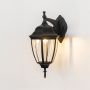 Illuminated black outdoor wall sconce on white background showcasing downward vintage coach lantern with clear glass glow.
