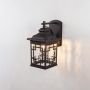 Black outdoor wall lantern light on white background turned on showing warm illumination.