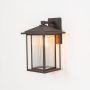 Black outdoor wall lantern light on white background showcasing modern rectangular frame and glass design.