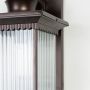 Closeup of brown metal outdoor lantern showing ribbed glass panels and detailed frame for premium exterior lighting.