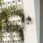 Lantern wall light installed near a wooden main door glowing warmly to enhance outdoor entrance decor.
