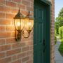Twin golden outdoor lantern with warm glowing lights mounted beside a green door creating a classic welcoming ambiance for exterior home entrances.