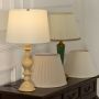 White shade beige spindle base table lamp on wooden sideboard with light off for warm traditional décor.