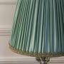 Closeup of elegant table lamp showing mint pleated fabric shade and crystal brass base highlighting its fine detailing and luxurious finish.