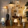Collection of table and floor lamps arranged in an elegant room with decorative vases warm lighting and classic wall paneling creating a cozy interior.