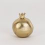 Gold pomegranate accent placed on a plain white backdrop showcasing its handcrafted metallic finish and seed detailing