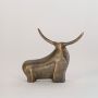 Textured bronze bull sculpture with raised horns and bold form clearly displayed on clean white background wall
