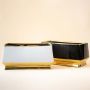 A modern pair of rectangular ceramic vases in glossy black and matte white finished with elegant gold bases displayed together on a wooden surface creating a balanced decorative look that highlights their contrasting colors and contemporary style.