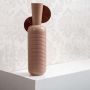 Modern ribbed ceramic vase in soft brown color shown on a clean white background highlighting its tall sculptural shape for home decor styling.
