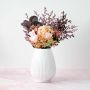 White ribbed ceramic vase placed on a white background highlighting its smooth glossy texture and elegant curved design.