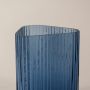 Closeup of ribbed blue glass vase showing vertical textured detailing and curved top edge for a refined and elegant look.