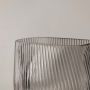 Closeup of smoky gray ribbed glass vase showing fine diagonal ridges and a smooth rounded base.