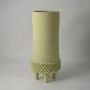 Matte light green ceramic vase with textured pattern and tripod legs on white background showing modern artistic decor.