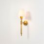 Illuminated brass wall lamp with glowing white fabric shade showing warm ambient light on clean white background display.