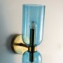 Closeup of double glass wall light showing transparent blue shades and sleek golden metal holder detailing.