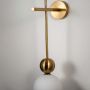 Closeup of wall lamp with frosted white glass globe shade and sleek gold finish frame showcasing elegant luxury wall lighting design.