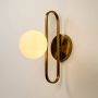 Wall light glowing with frosted white glass globe and gold frame creating warm ambient illumination for modern interior walls.
