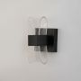 Black wall light with curved acrylic shade presented on a white background with lights off.