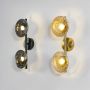 Set of modern black metal wall sconces with illuminated smoked glass globes arranged together on pristine white surface.