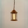 Copper hanging lantern on white background with light on showing warm glow through clear glass panels and classic metal top ideal for balcony and porch lighting.