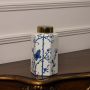 White ceramic jar with blue floral butterfly design and glossy golden lid perfect for elegant modern interiors.