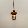 A golden hanging lantern with light off against a white background showing its patterned glass panels and intricately crafted metal frame in clear detail.
