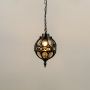 Illuminated black metal sphere pendant light with decorative cage design and warm bulb glowing against a plain white background.