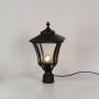 Black metal pillar lantern glowing softly with ribbed clear glass ideal for outdoor home entrances and garden pathways.