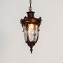 Closeup highlighting intricate carved detailing and glass texture of antique brass hanging lantern light.
