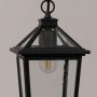 Detailed closeup of a black outdoor lantern showing the textured clear glass panels and sleek frame design with visible bulb details on a white background.