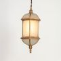 A golden hanging lantern with the light on displayed on a white background showing its glowing frosted panels dome shaped top and decorative metal frame for elegant lighting.