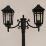 Close up view of black double lantern post light showing grid pattern glass panels curved arms and decorative finials.