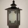 A closeup view of the outdoor lamp head showing the intricate geometric border design around the frosted glass panel with crisp detailing on the dark metal structure.
