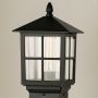 Closeup of black outdoor pillar lamp showing clear framed glass and warm filament bulb detail suitable for elegant garden and pathway lighting.