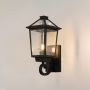 Black outdoor wall lantern with glowing warm bulb shown on a clean white background for classic exterior lighting decor.